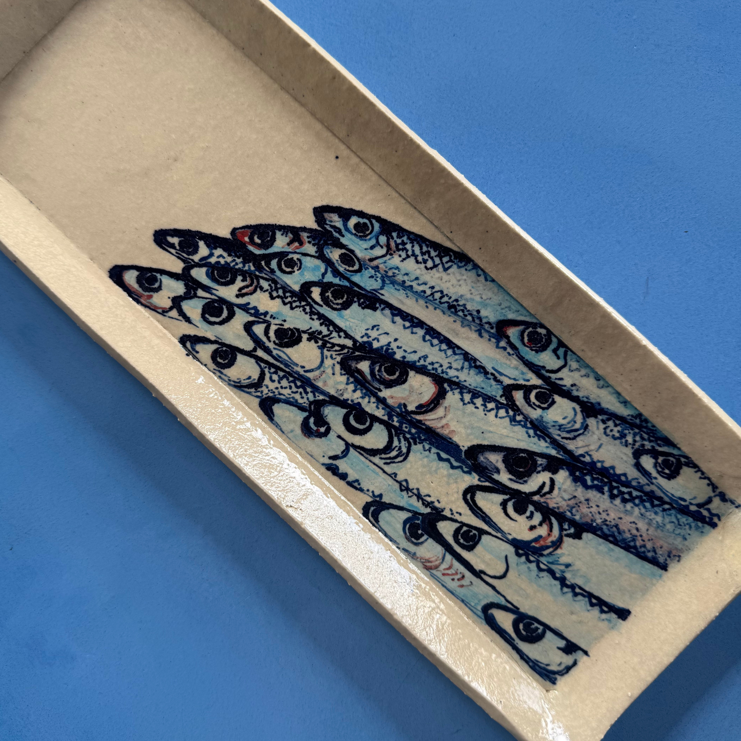 Close-up van de handgeschilderde sardientjes met verfijnde penseelstreken en zachte kleuraccenten.