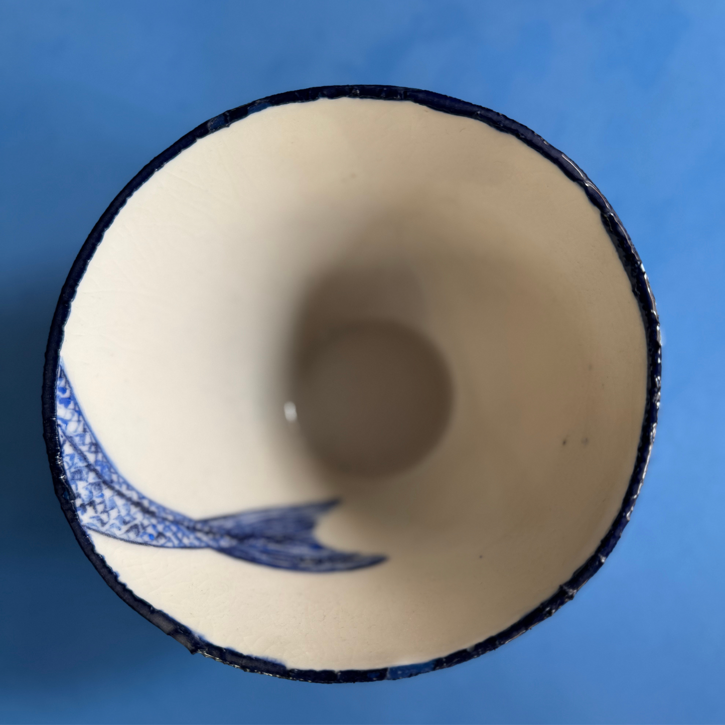 Top-down weergave van de kleine kom met alleen de handgeschilderde visstaart in het interieur.