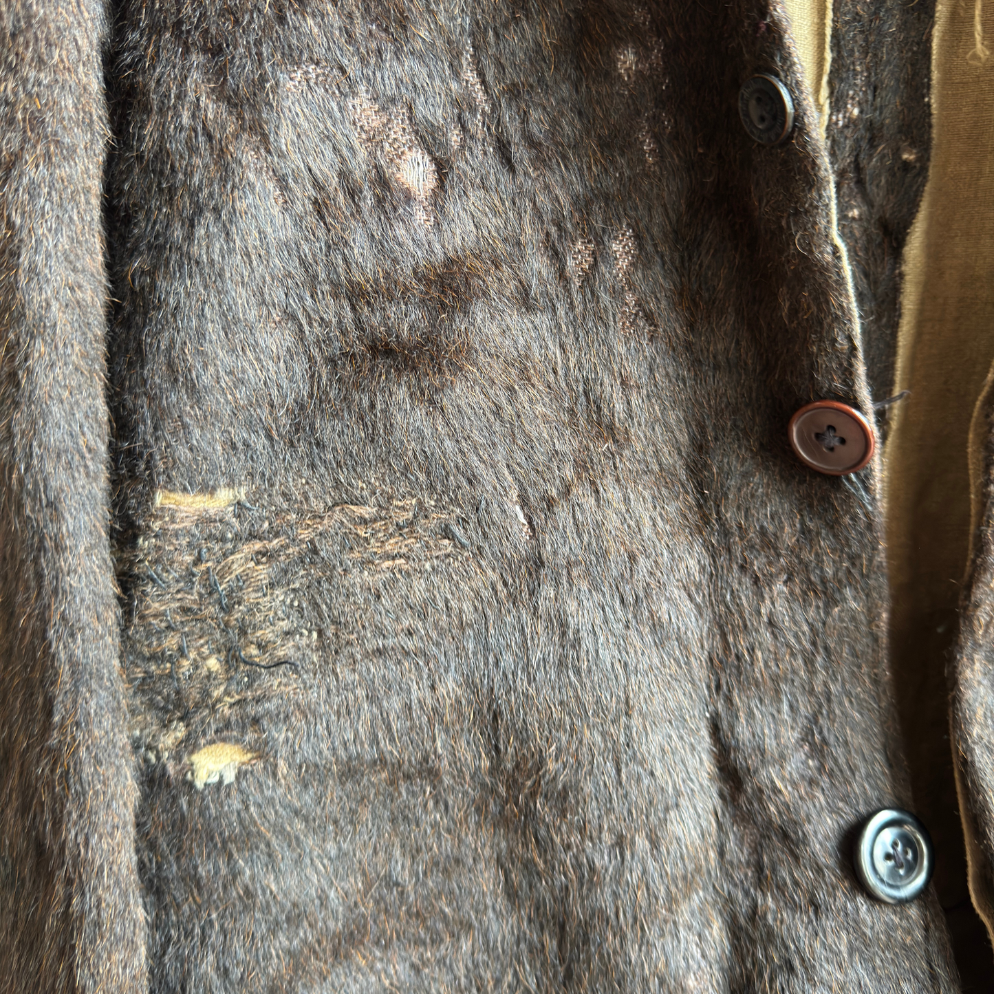 Close-up of patched repair on bear suit revealing frayed wool-felt and cotton lining