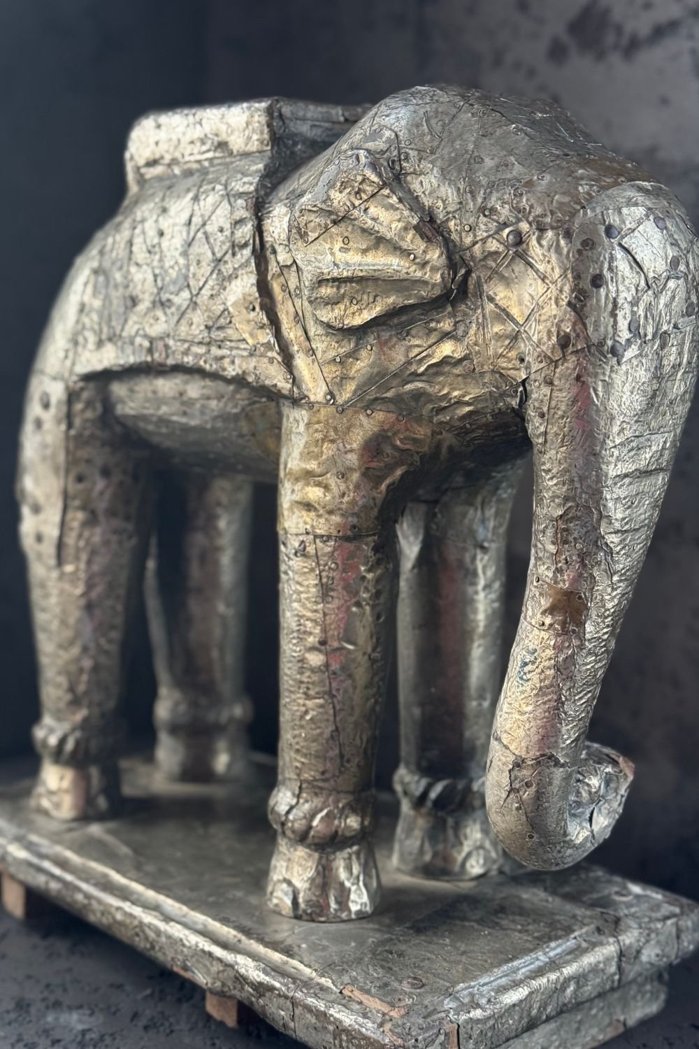Close-up of a ceremonial gilded elephant sculpture showing textured metal foil and hammered surface details.