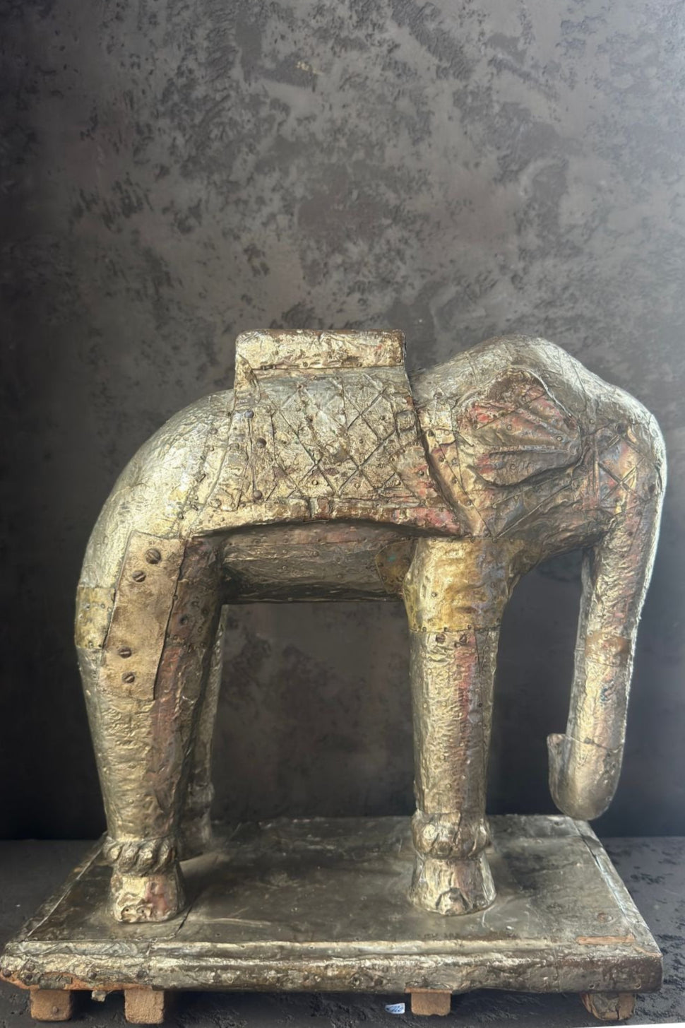 Side view of the vintage elephant sculpture on a wooden base, wrapped in aged gold and silver foil.