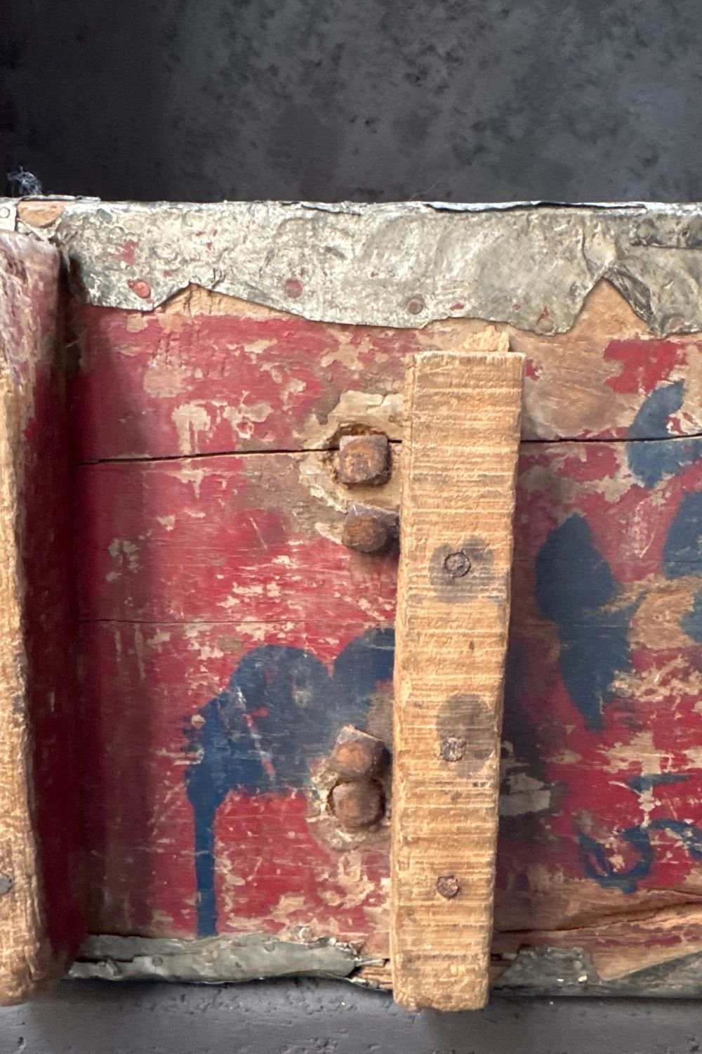 Close-up of the base of the sculpture showing the aged wood, original red paint, and metal trim.