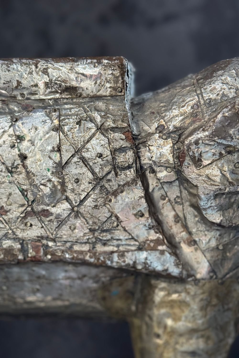 Detail of the saddle area of the sculpture showing hand-applied foil with intricate hammered patterns.