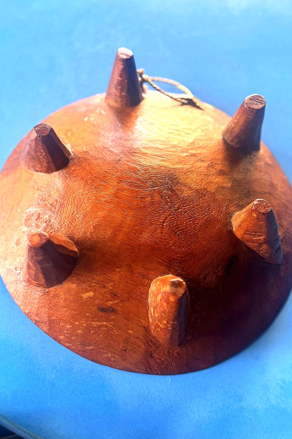 Underside of hand-carved wooden Fijian bowl showing six conical legs