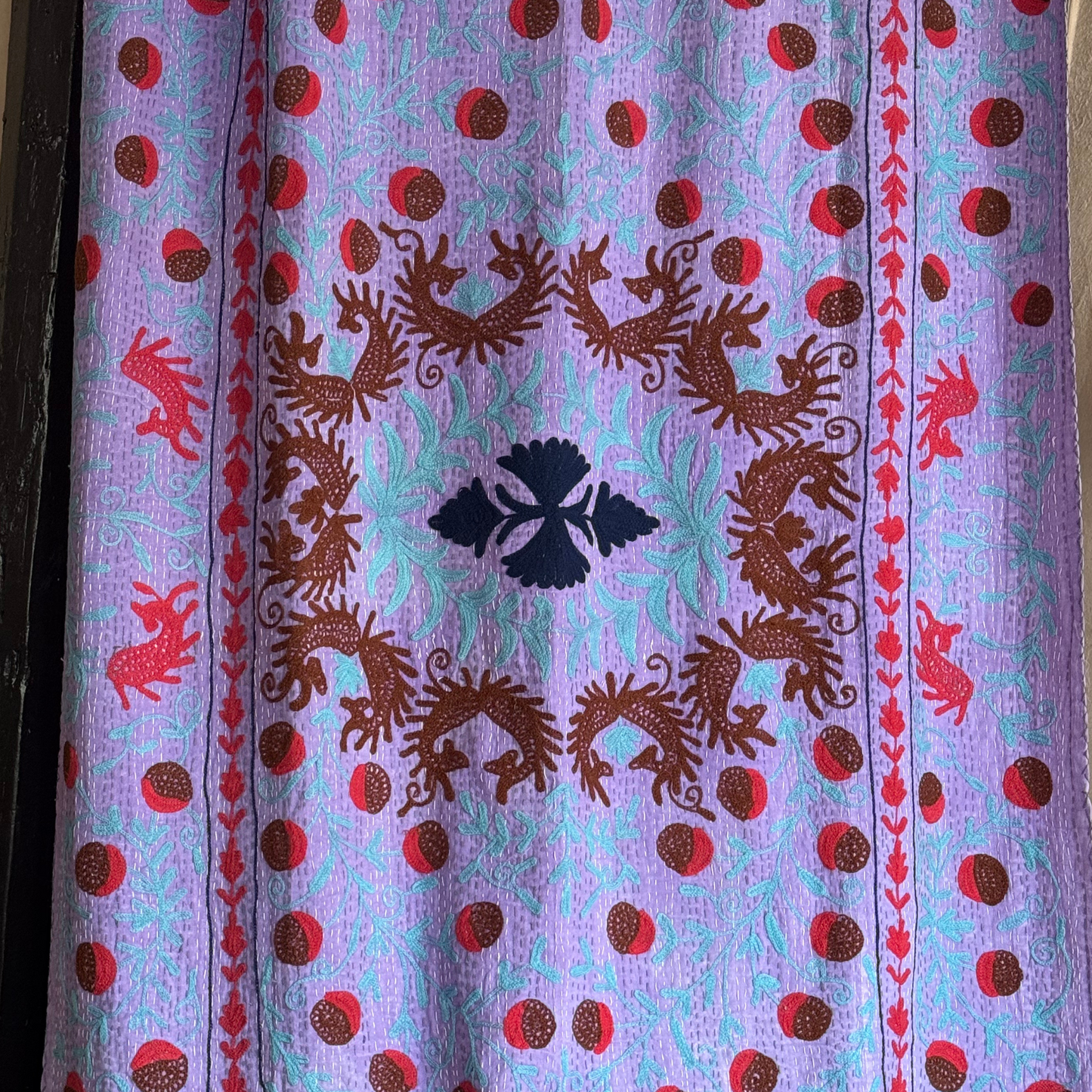 Close-up of center design featuring horses or deer, stylised florals, and bold outlines