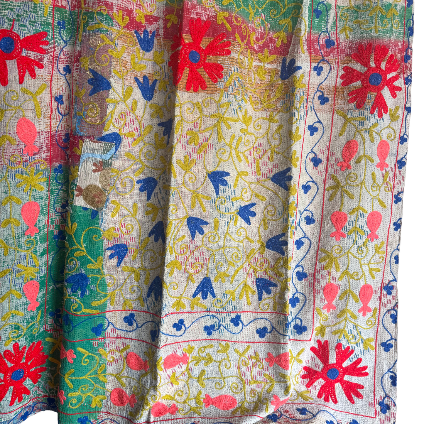 Close-up of neon-coral pomegranate embroidery and chartreuse vine scroll on cotton Kantha throw