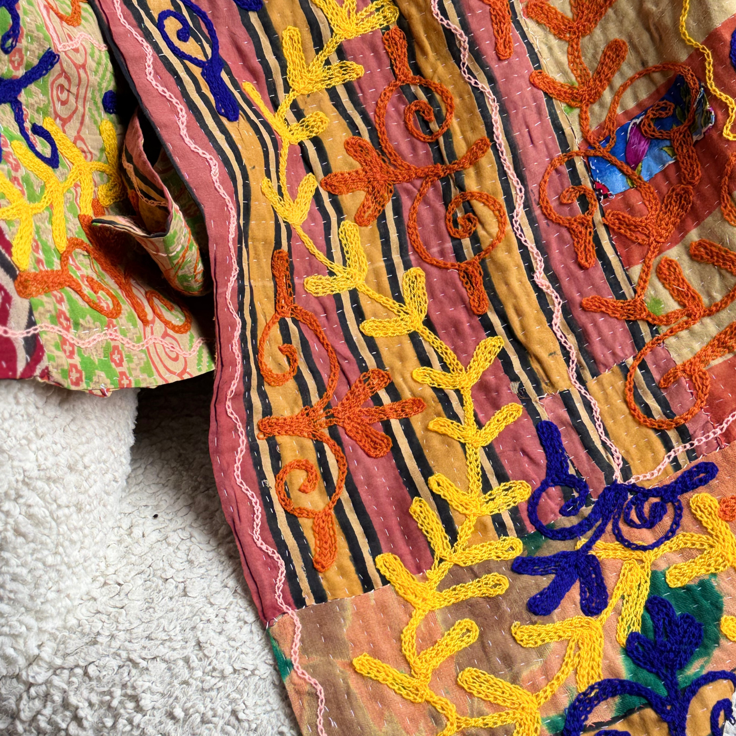 Close-up of kantha embroidery with chain-stitched floral patterns in yellow, orange, and purple