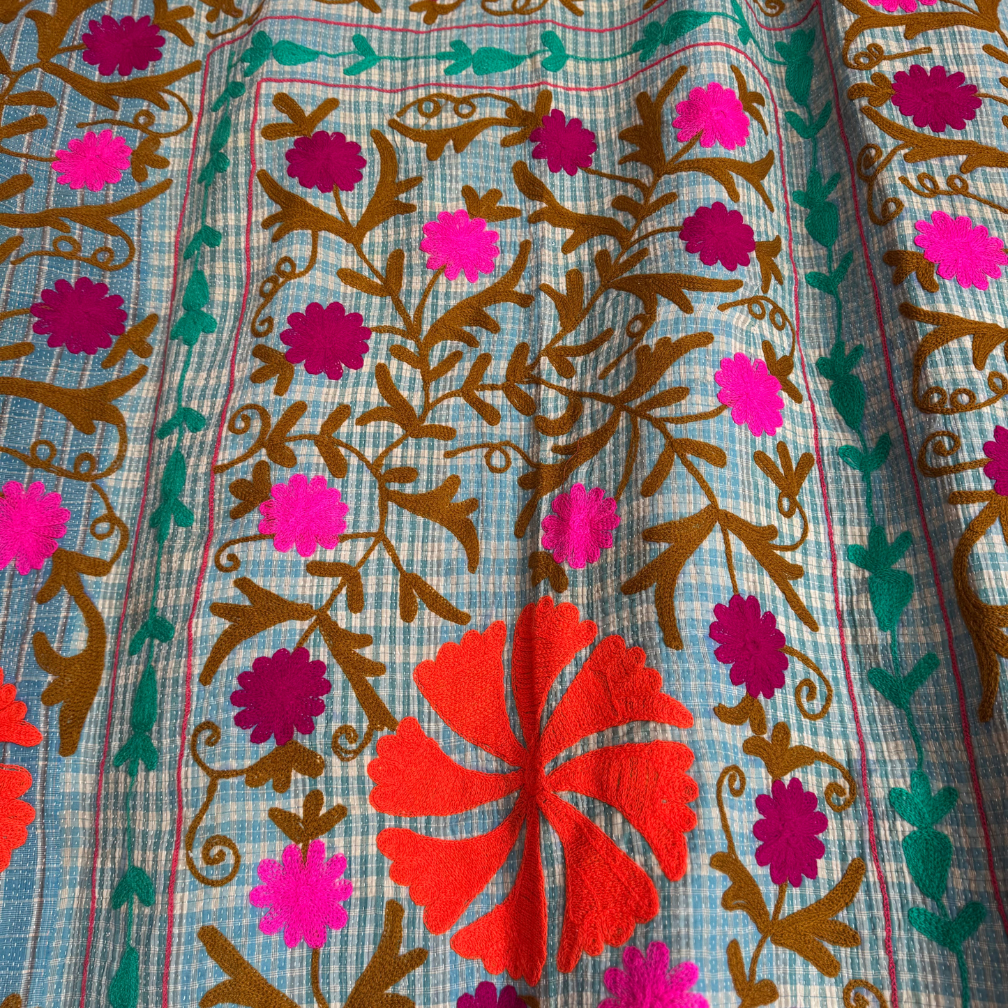 Detail of vibrant orange floral medallion against check background