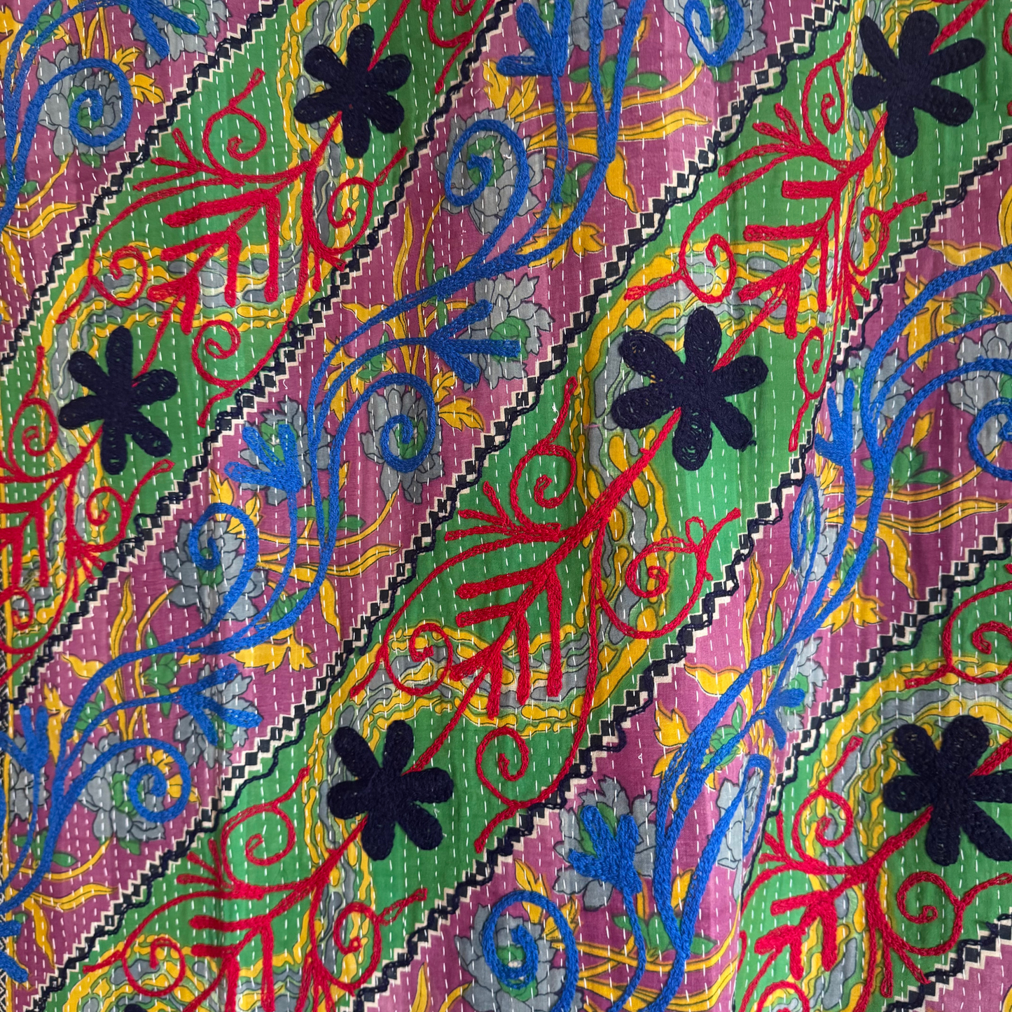 Detail of vivid diagonal stripes in fuchsia, green, cobalt and scarlet under running stitch