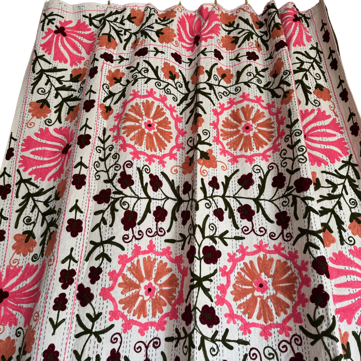 Detail of fuchsia-pink floral medallion embroidery showing layered running stitches