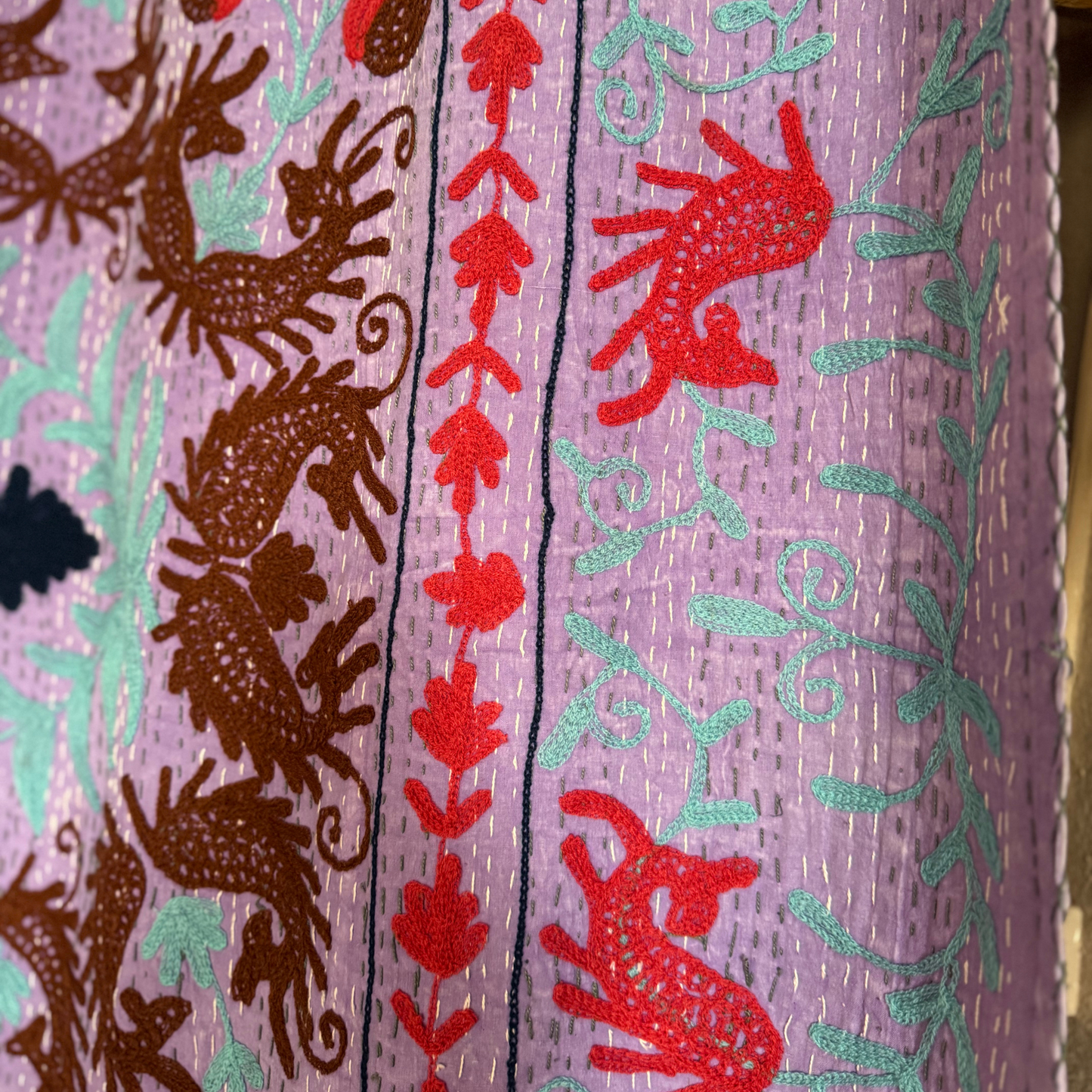 Edge detail of kantha with floral border, vines, and hand-quilted running stitches