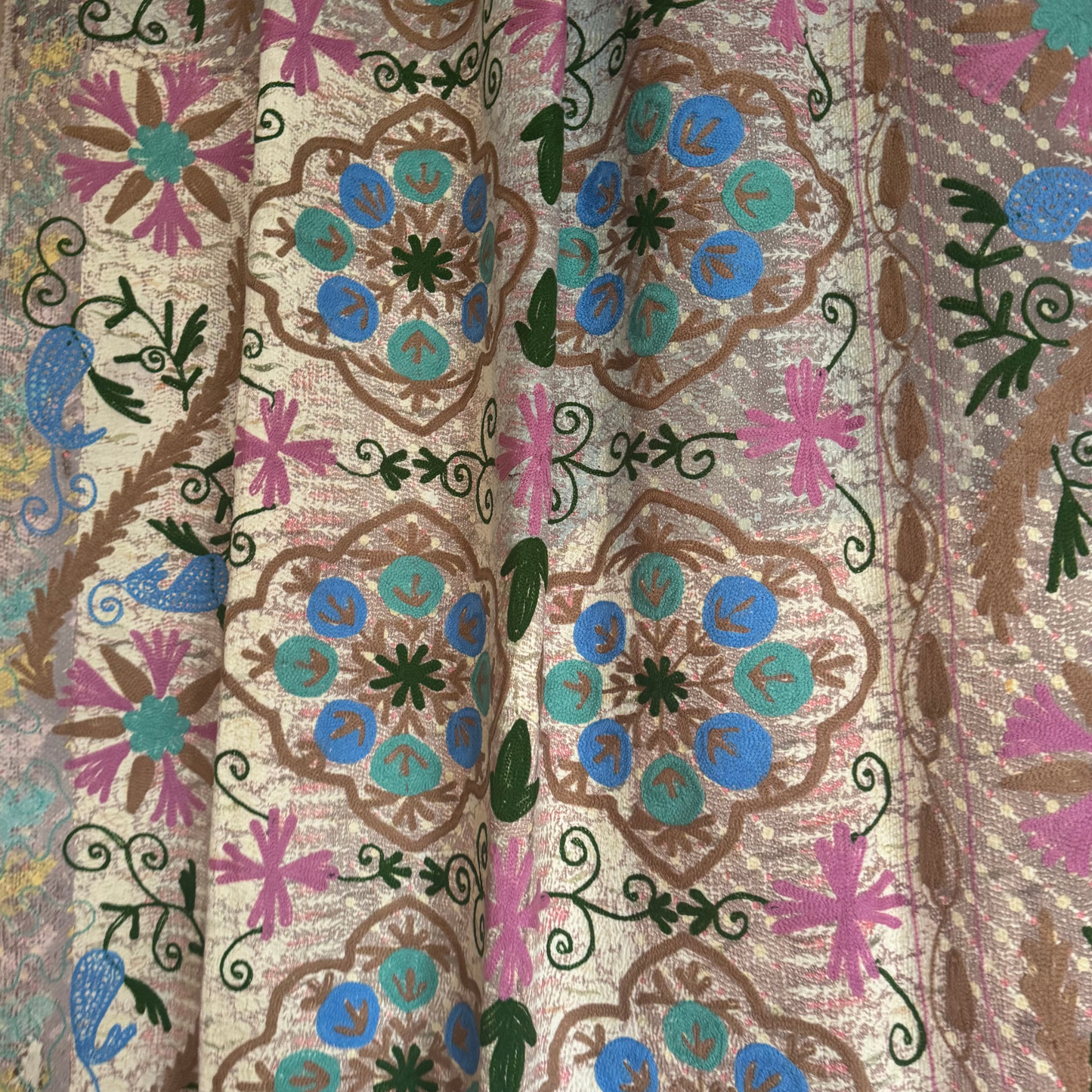 Detail showing painterly pastel pink, buttery yellow, and soft grey washes on repurposed sari cotton with running stitches