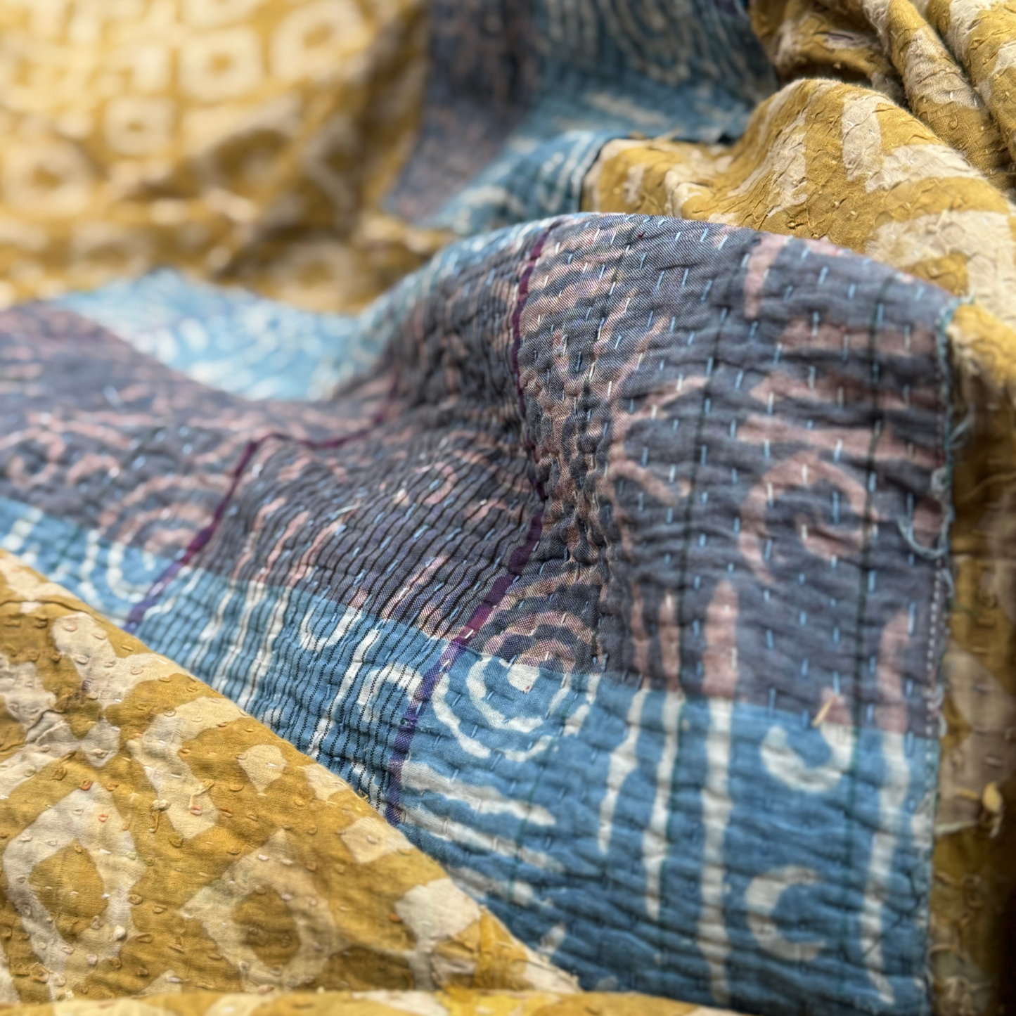 Close-up of kantha quilted texture and running stitch over blue and indigo block print patches