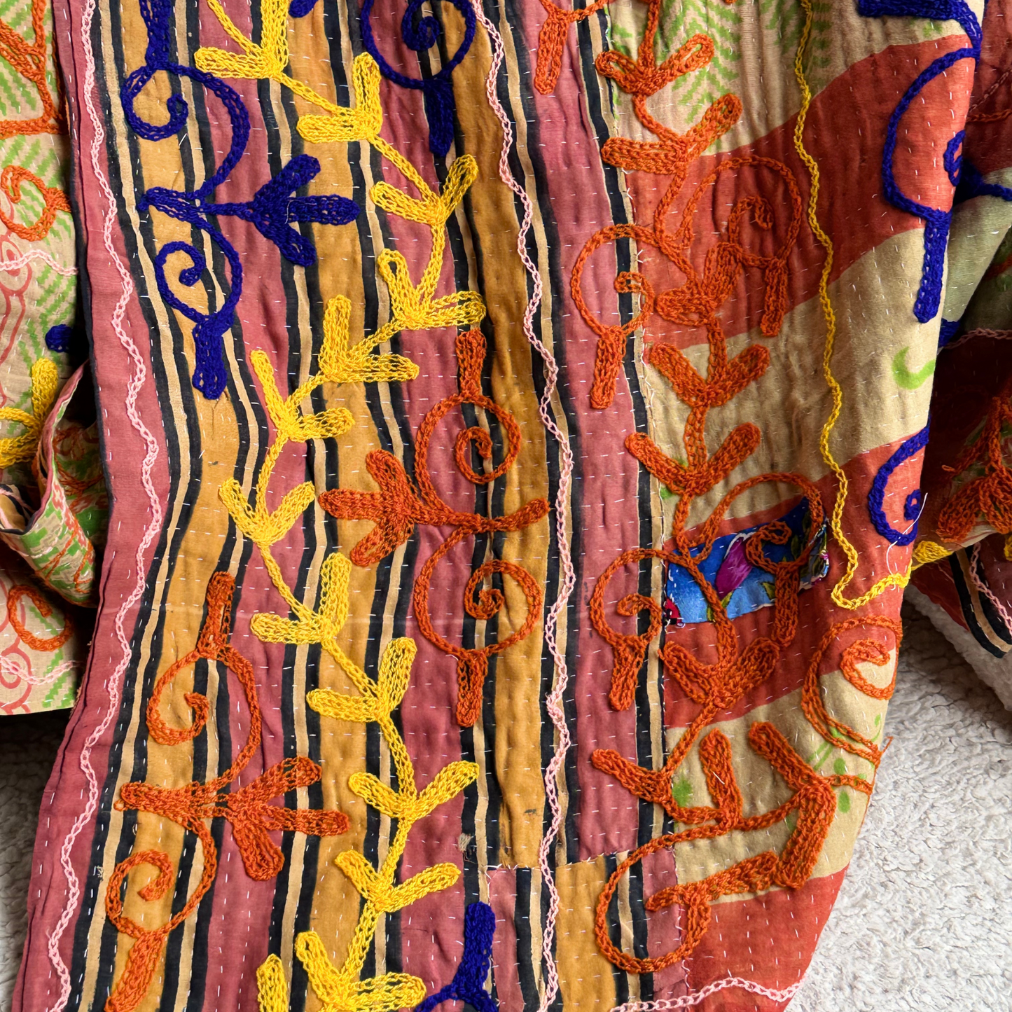 Folded kantha textile showing layered sari fabric and vibrant embroidery details
