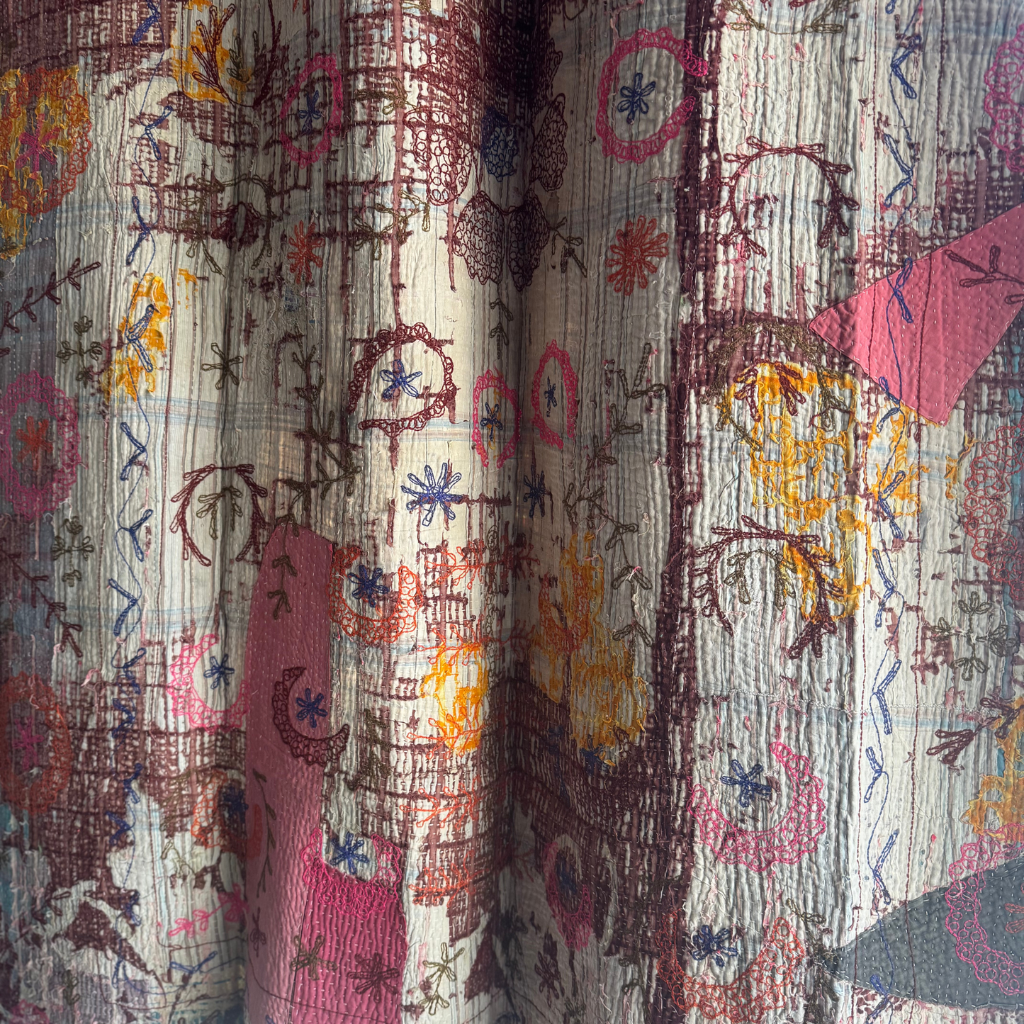 Close-up of back panel showing brown vine embroidery over blue-beige patchwork