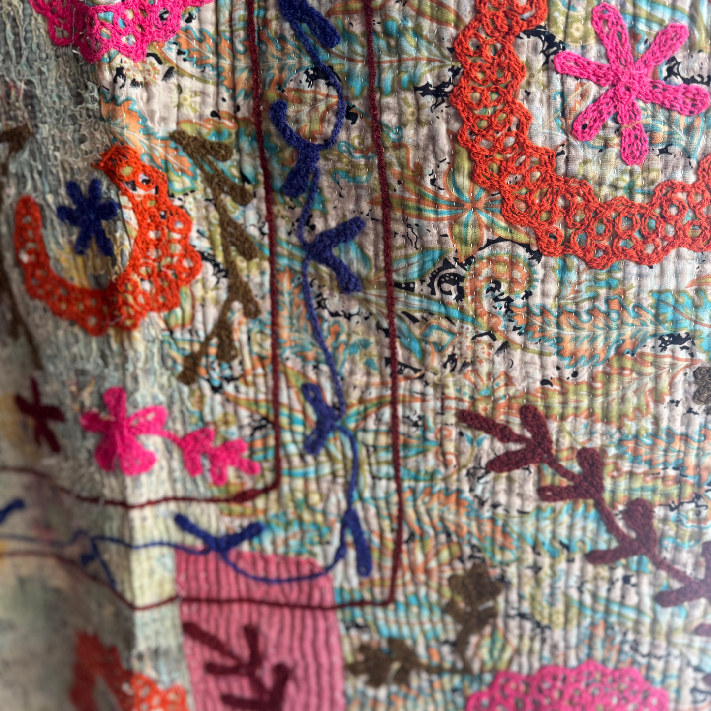 Close-up of burgundy flower motifs and beige running-stitch background