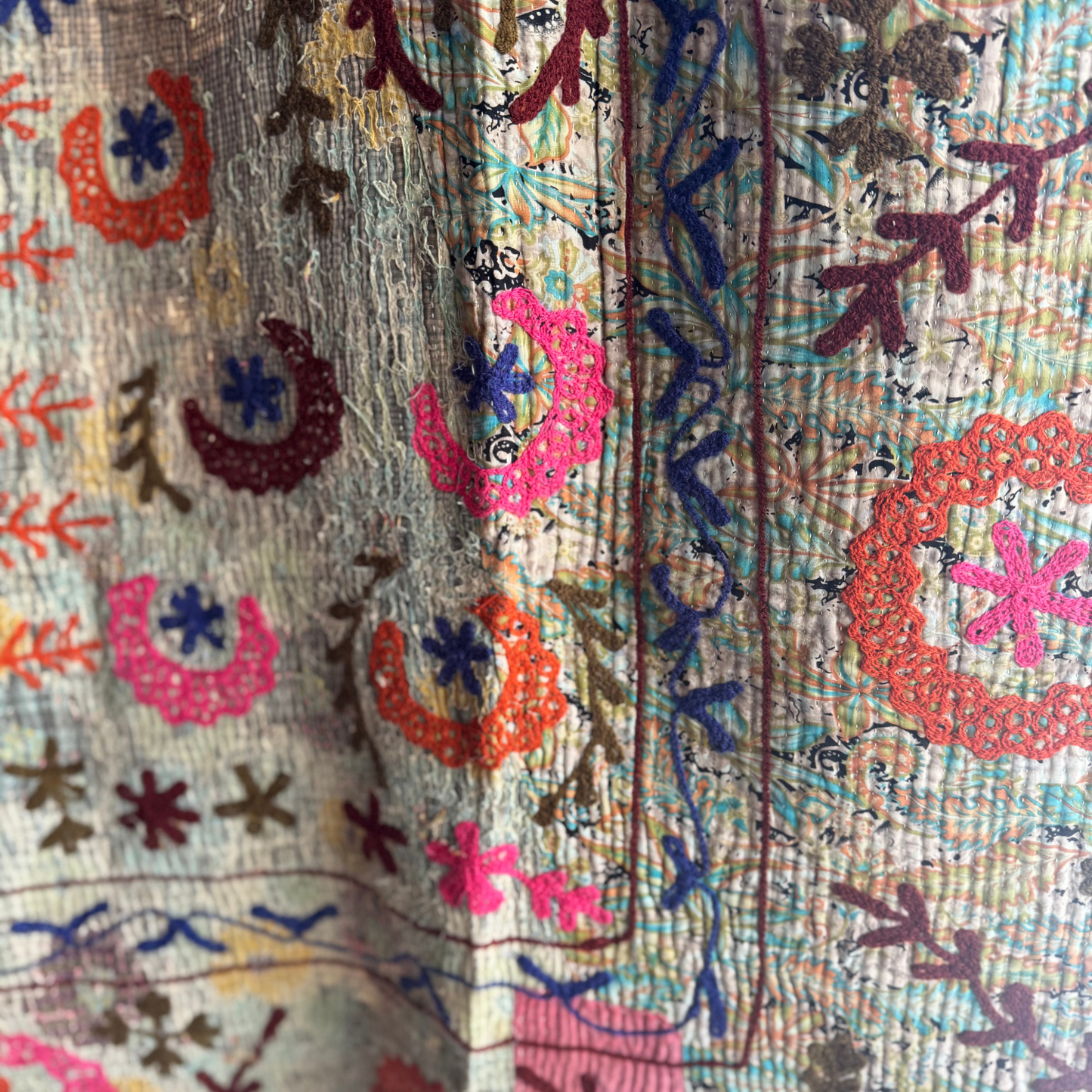 Detail of light-green vine embroidery on beige fabric