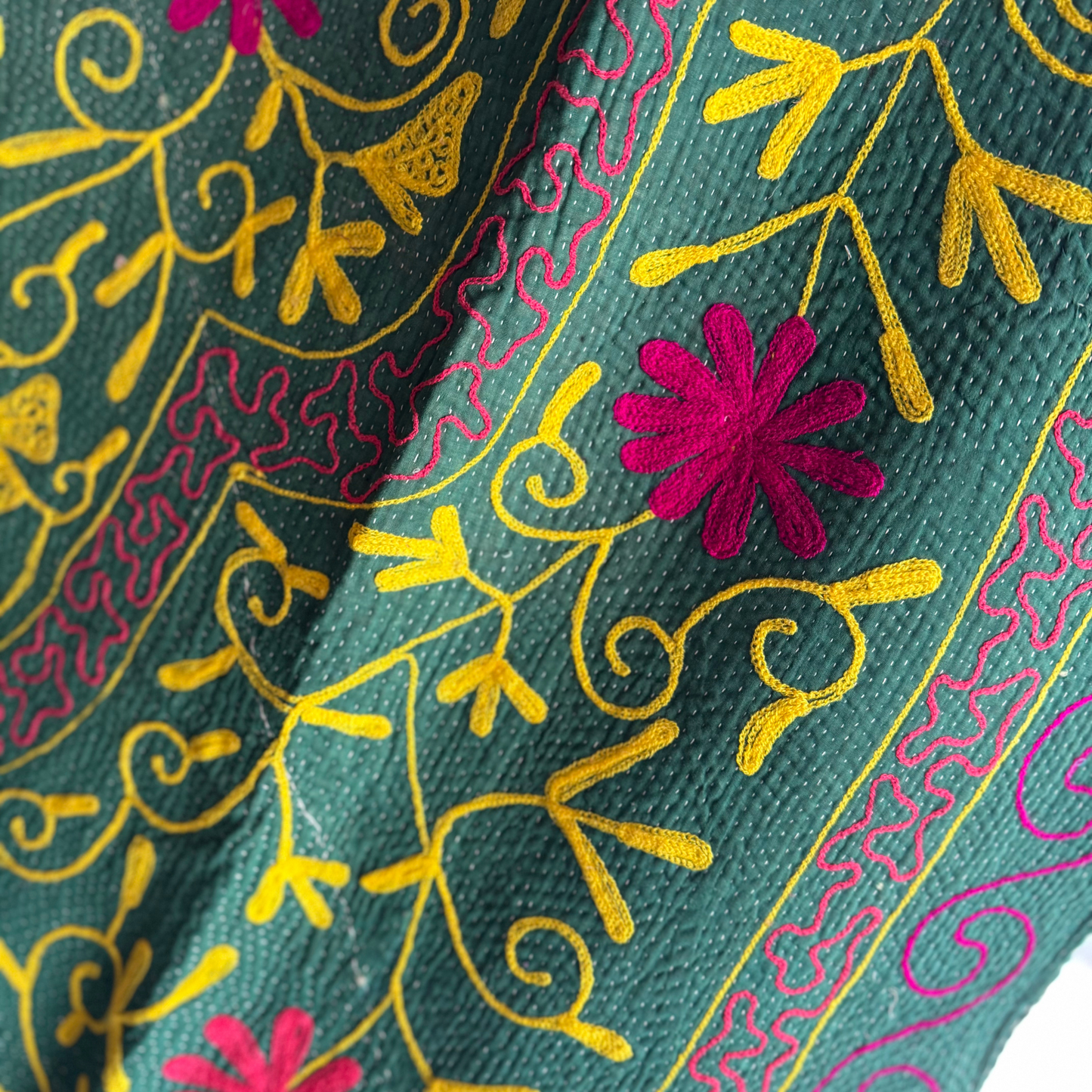 Detail of green panel showing yellow vine embroidery and pink floral accents