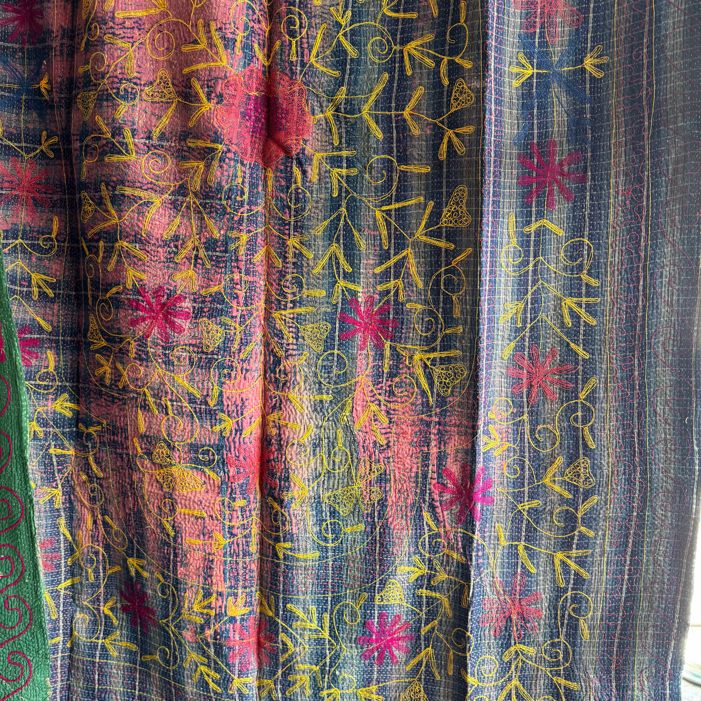Detail of blue panel showing yellow vine embroidery and pink floral accents