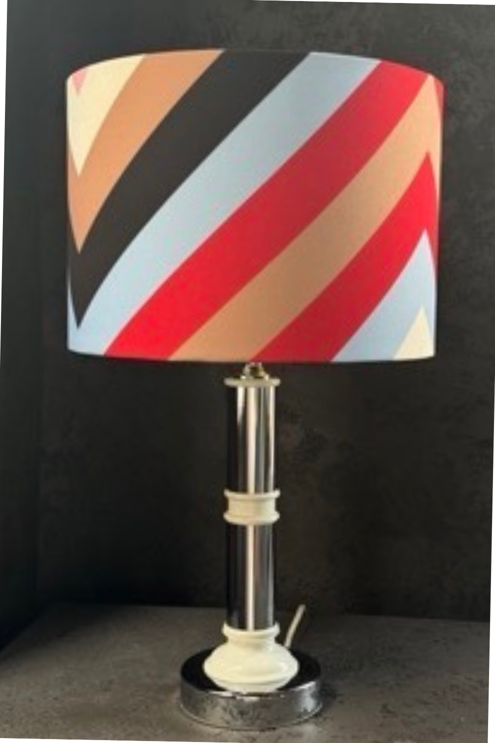 Mid-century style lamp with metal column and white ceramic base, showcasing a modern and minimalistic design.
