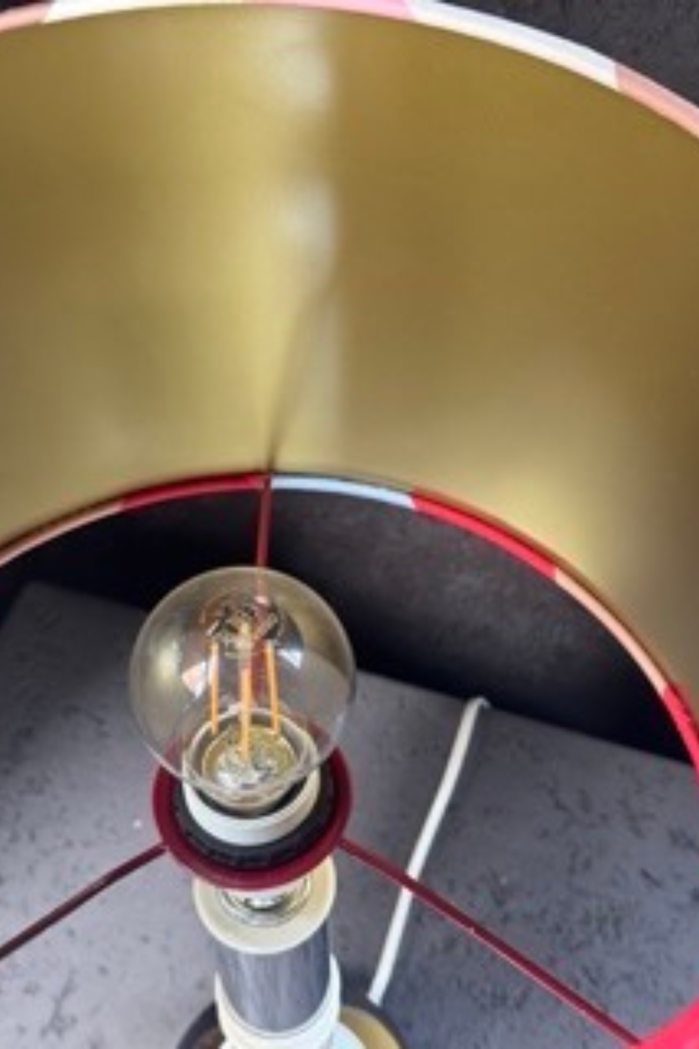 Full view of the mid-century style lamp, combining a metal column with a white ceramic base and a colorful handmade striped lampshade.