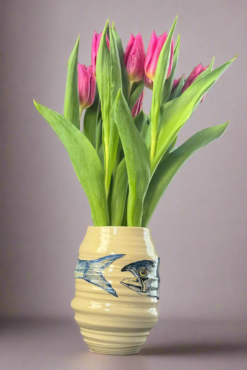 Hand-painted ceramic vase by QM Ceramics with a blue fish design, displayed with pink tulips. Height 19cm, diameter 11cm.