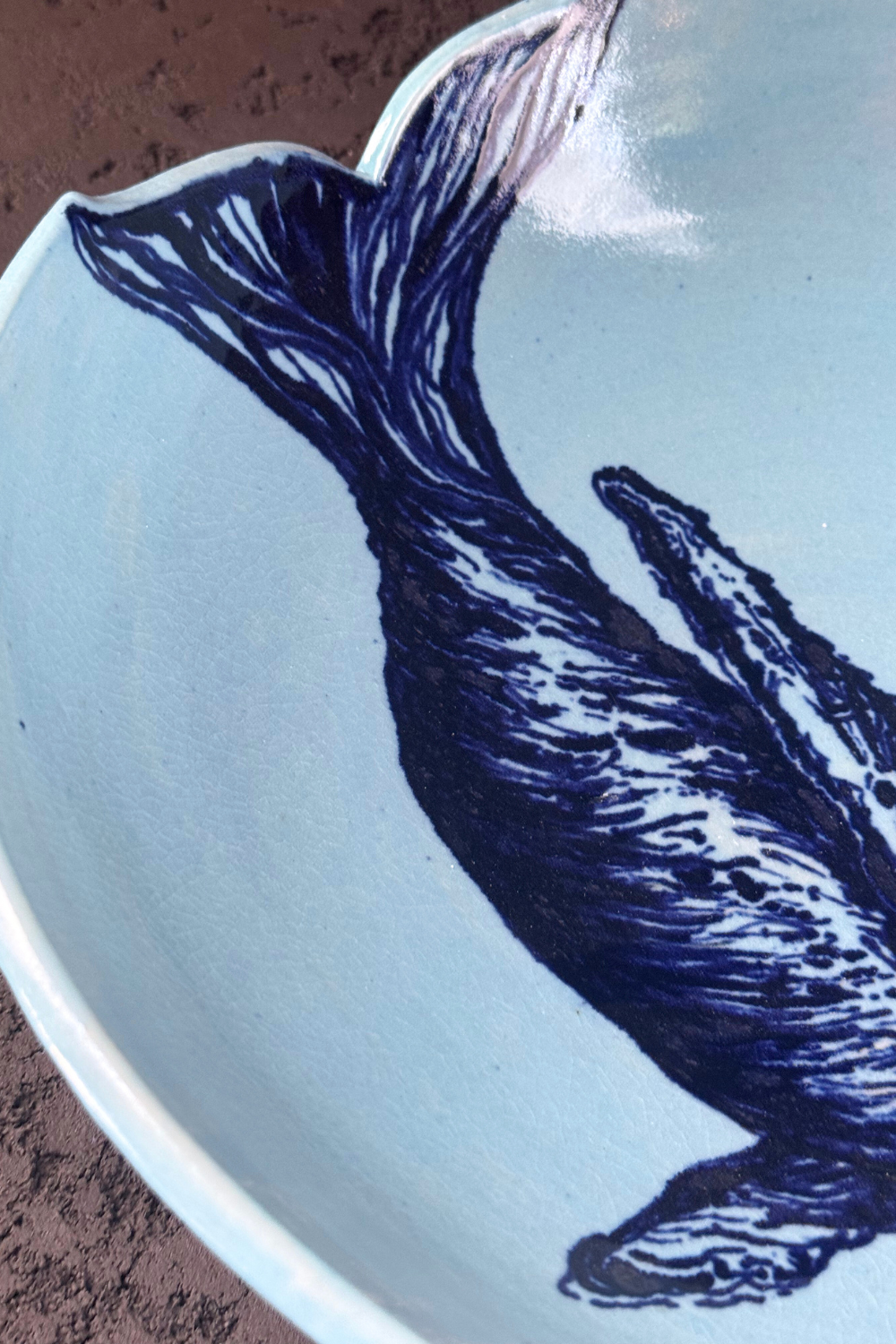 Close-up of the hand-painted whale illustration on the QM Ceramics bowl. Fine brushwork on soft blue ceramic glaze.