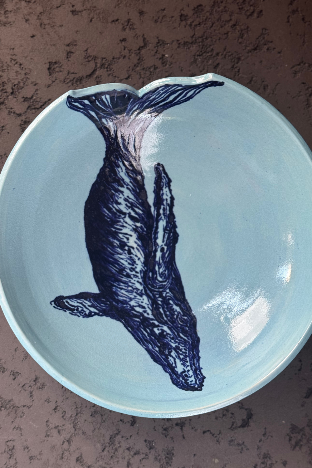 Large ceramic whale bowl by QM Ceramics, top view. Features a hand-painted whale design on a soft blue glaze, with a unique tail cut-out.
