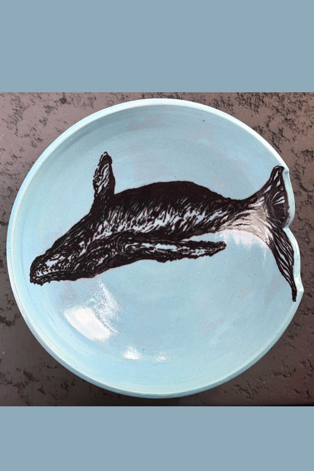 Handcrafted ceramic whale bowl by QM Ceramics, top view. Soft blue glaze with a hand-painted whale illustration and sculptural tail cut-out