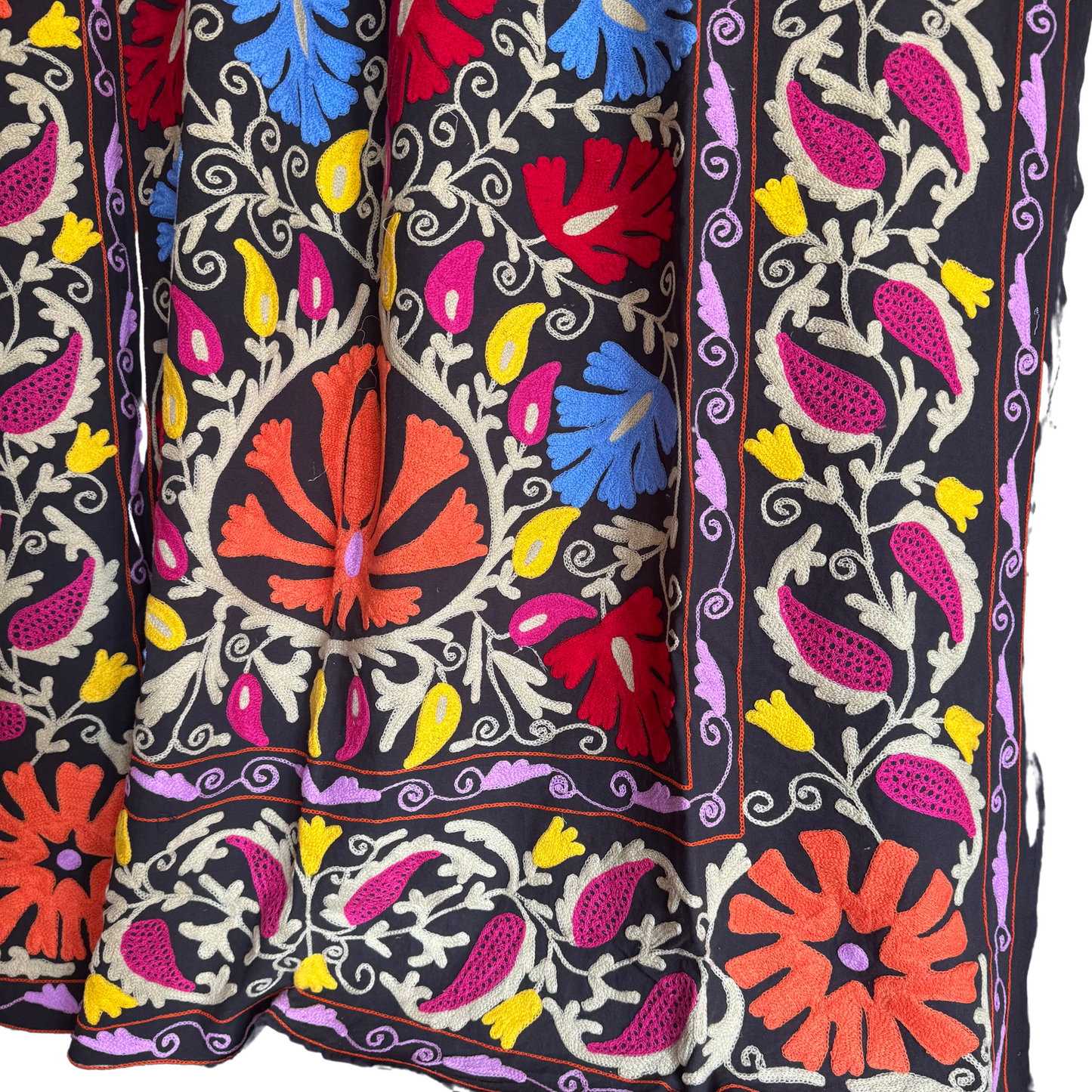 Close-up of lilac and purple embroidery in dense chain-stitch on washed-black ground