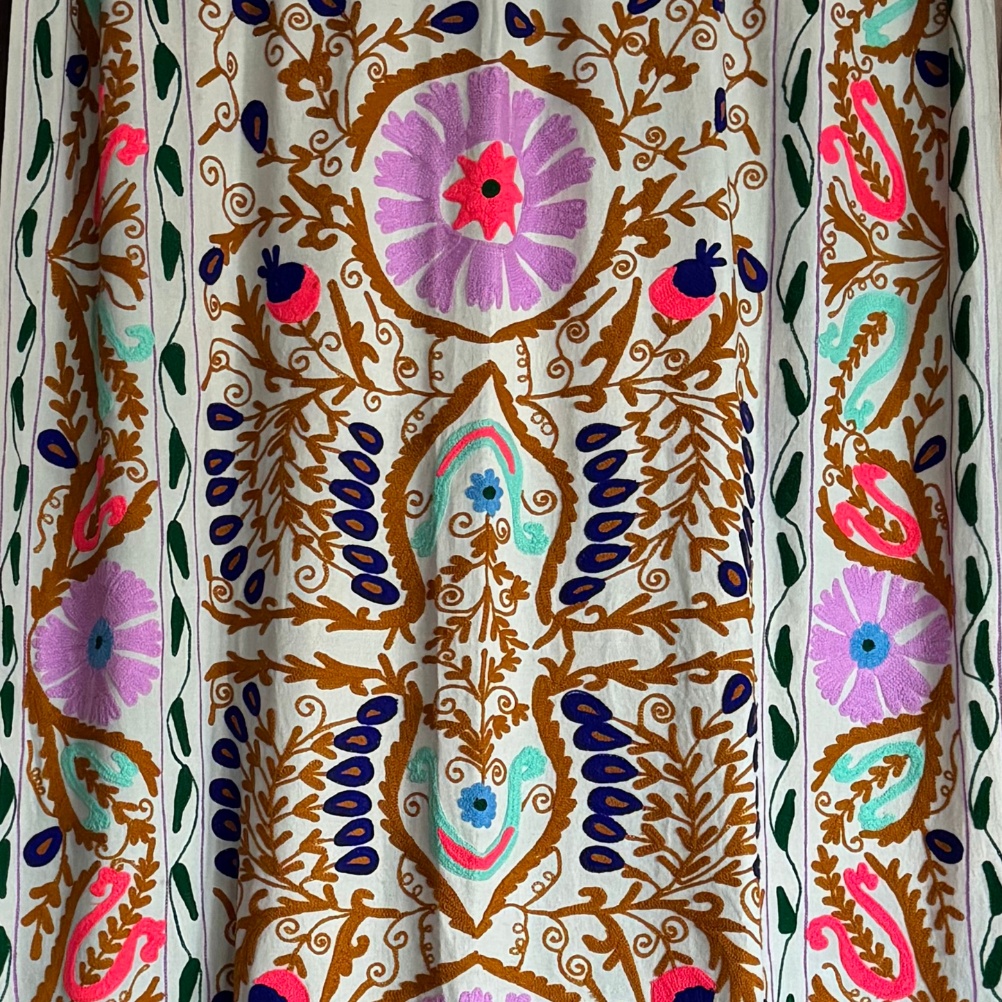 Central embroidery detail with bold floral and botanical motifs in vivid colours on pale green cotton