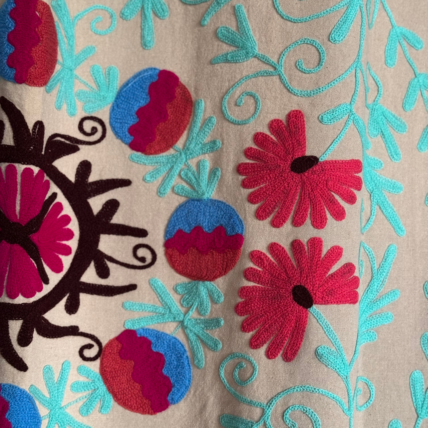 Detail of Suzani's central motif with circular forms and fuchsia accents on light background