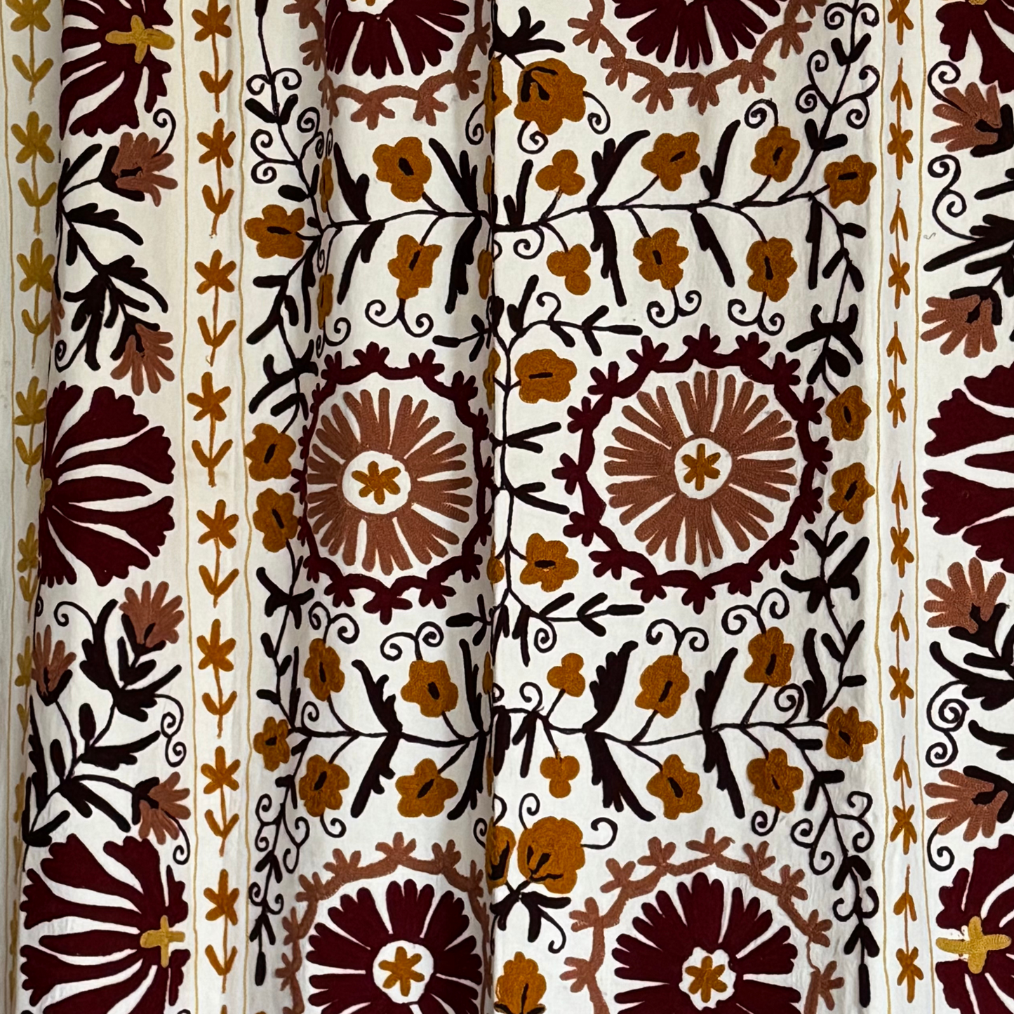 Detailed embroidery in maroon, mustard and black threads on ivory base