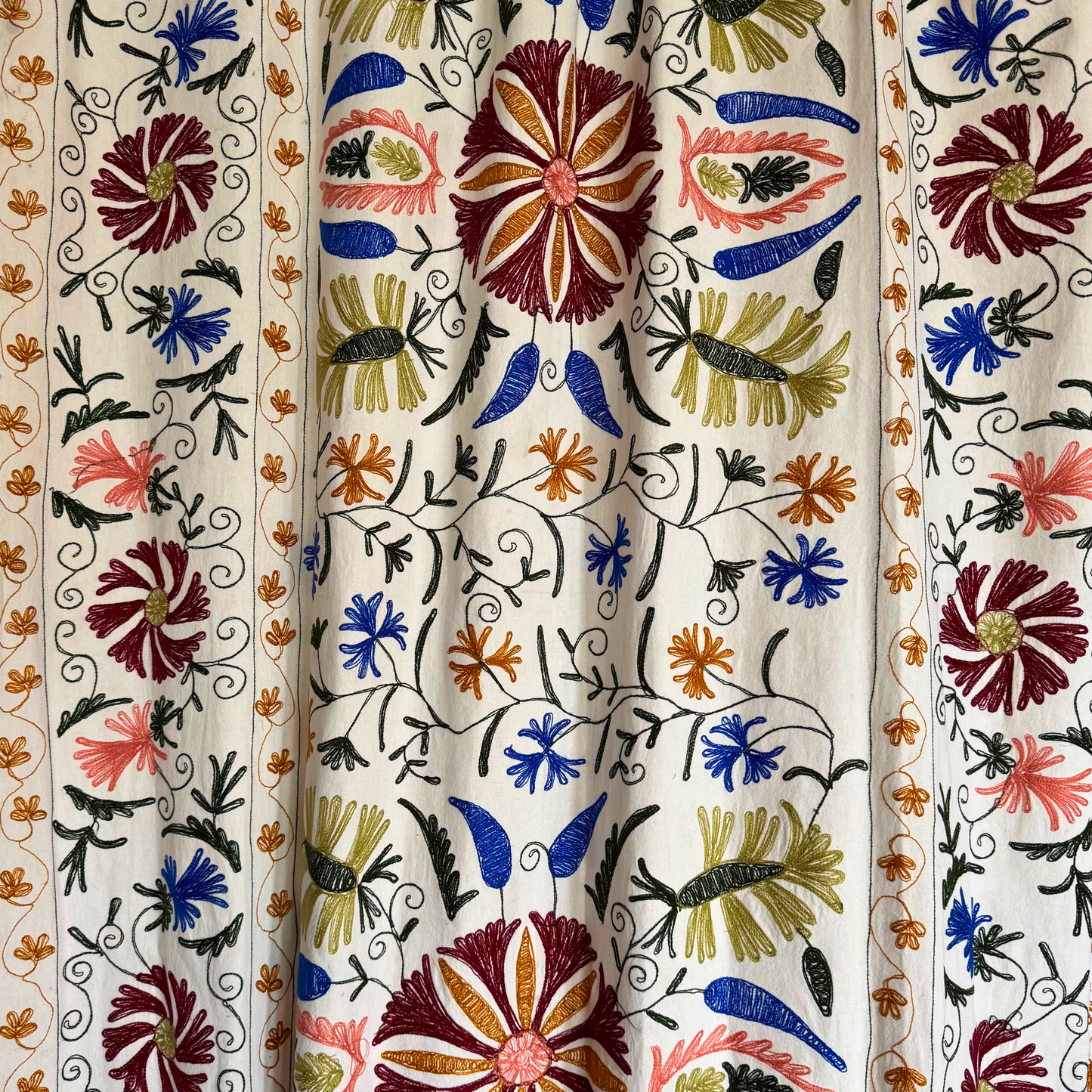 Suzani used as wall hanging behind console table in bright, modern interior