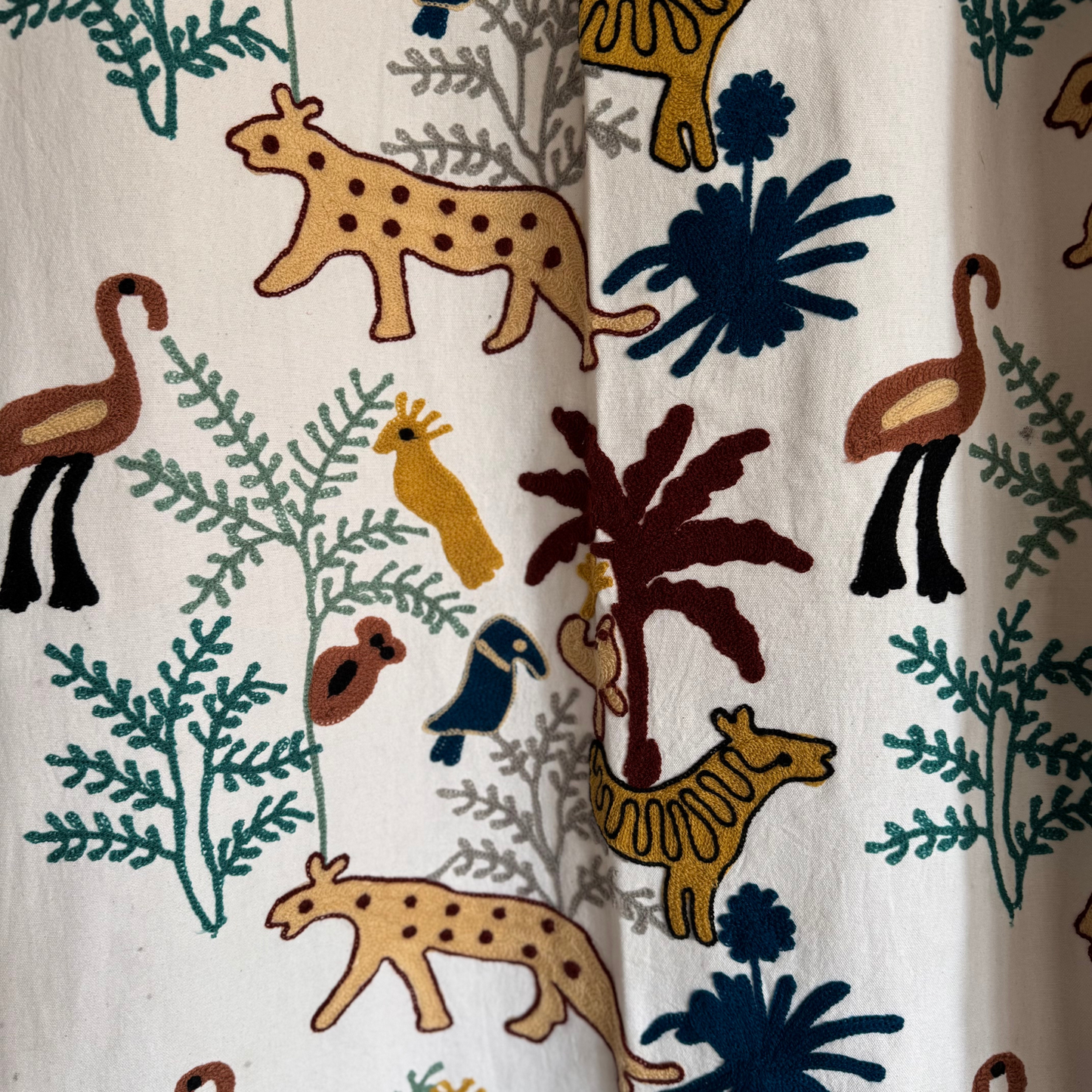 Detail showing navy-blue toucan and emerald-green fern chain-stitches