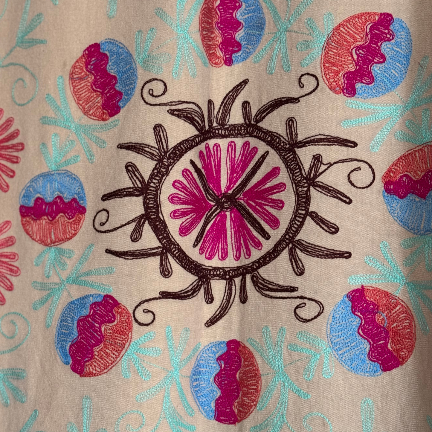 Suzani used as a decorative wall textile with bold flowers and curling vines