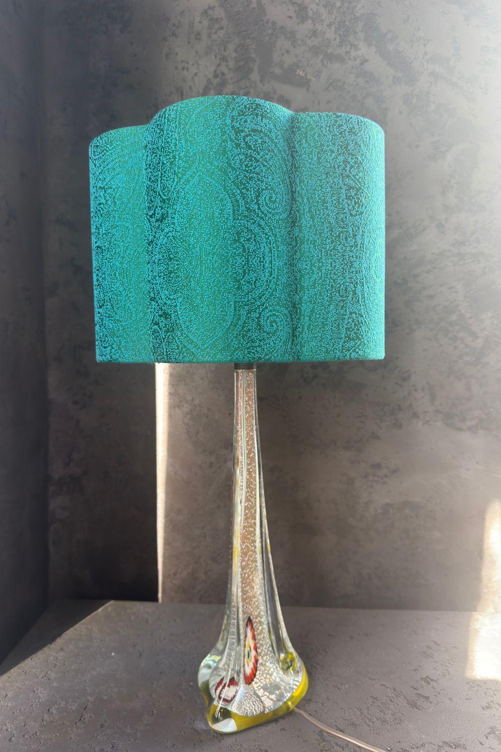 Vintage glass lamp with green shade, featuring colorful patterns on the base and a distinctive design.