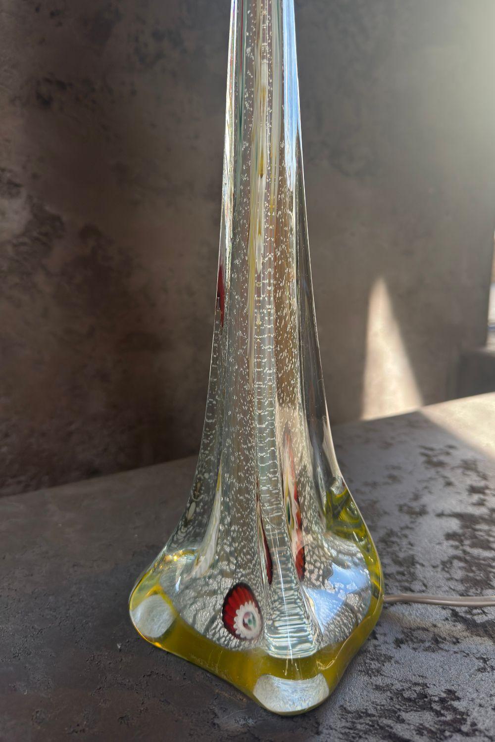 Side view of a vintage glass lamp, emphasizing the glossy glass base with artistic colorful accents.