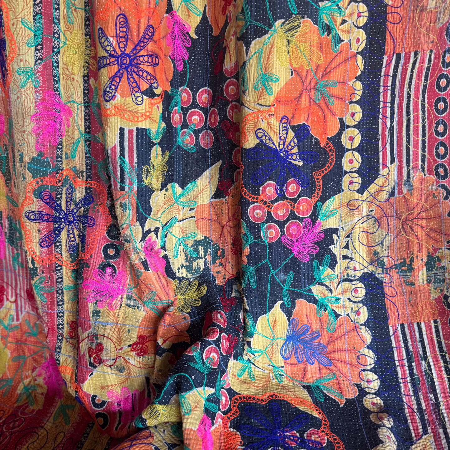 Back-side close-up of olive-green vine scroll embroidery on reversible Kantha blanket