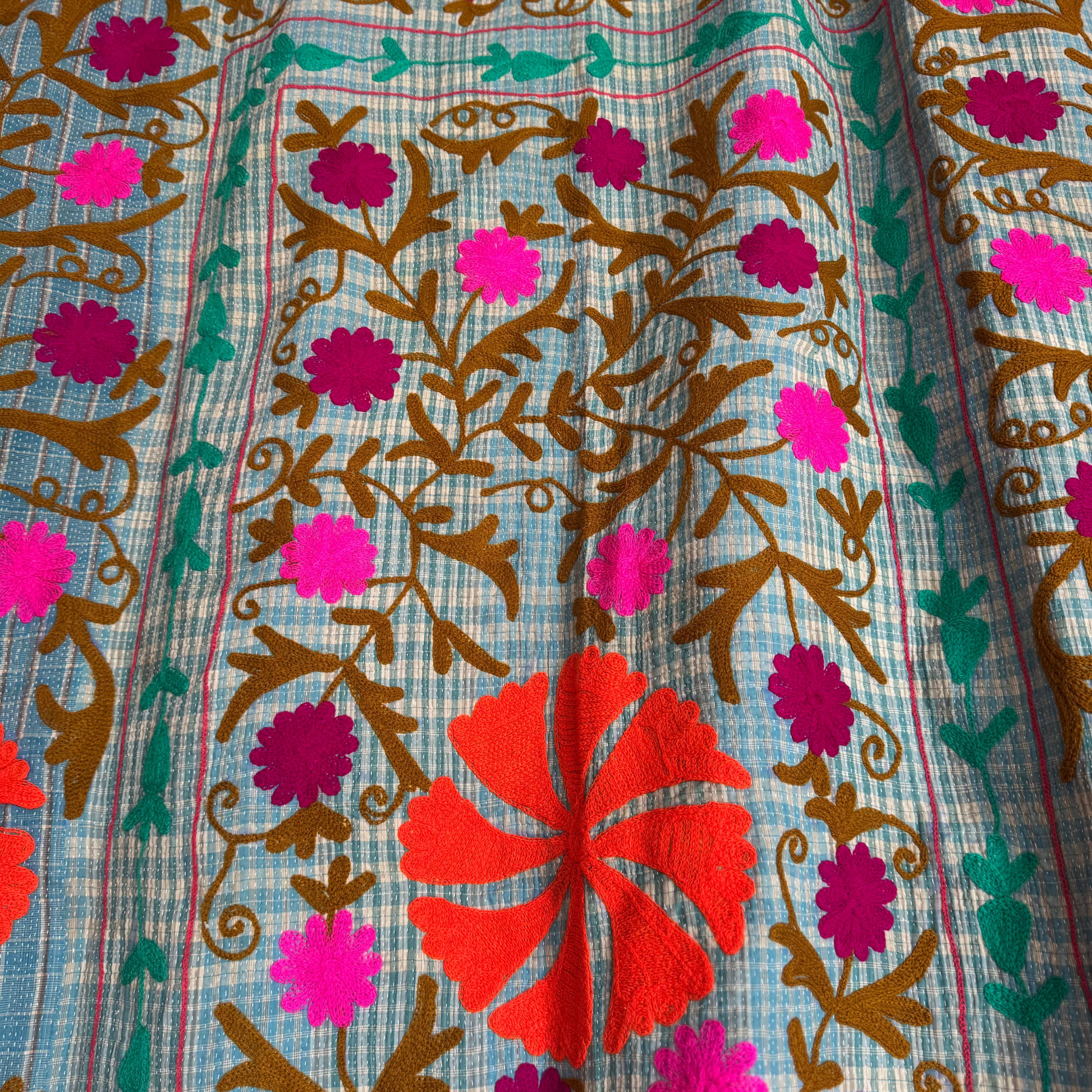 Detail of vibrant orange floral medallion against check background

