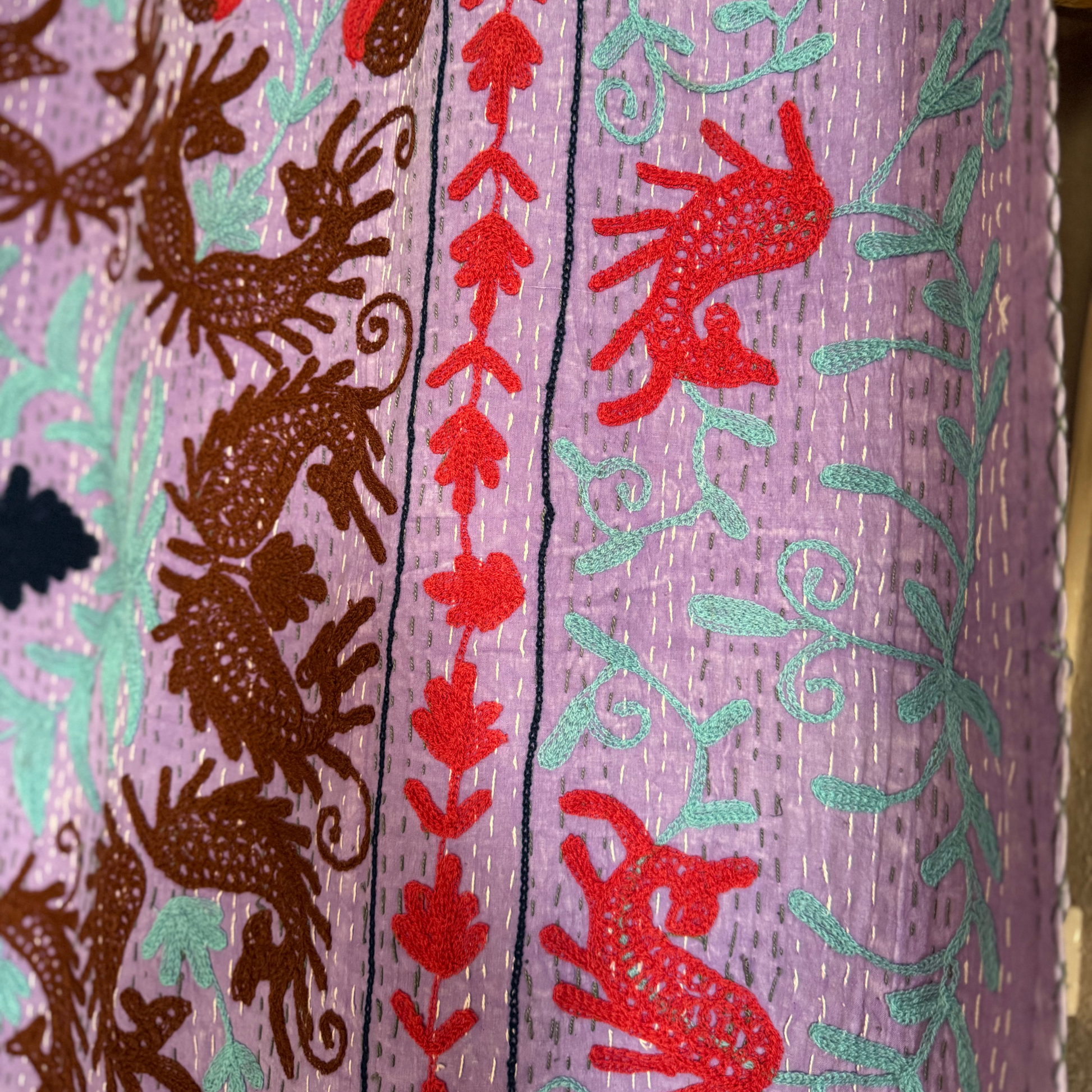 Edge detail of kantha with floral border, vines, and hand-quilted running stitches