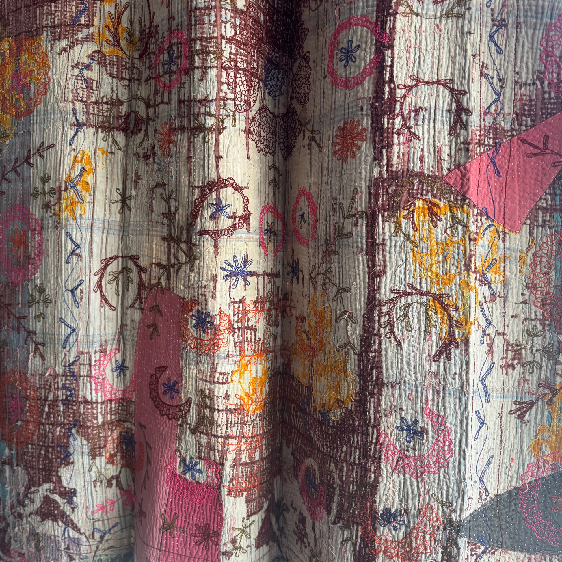 Close-up of back panel showing brown vine embroidery over blue-beige patchwork