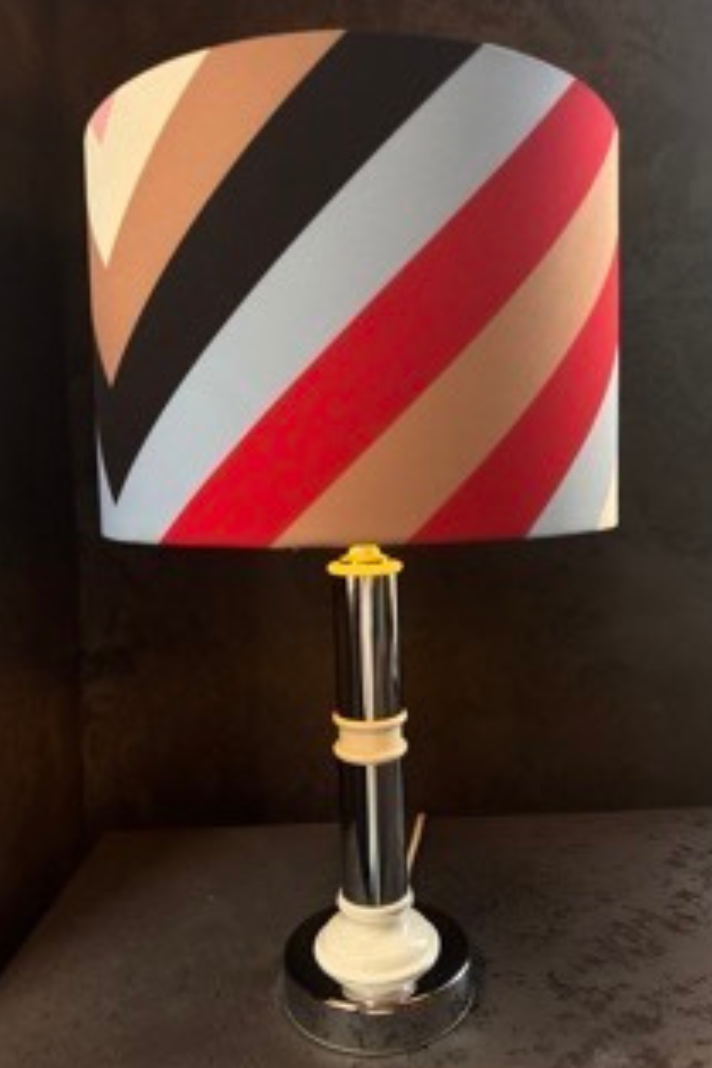 Mid-century style lamp with colorful handmade striped lampshade, creating a vibrant and stylish contrast to the sleek base.