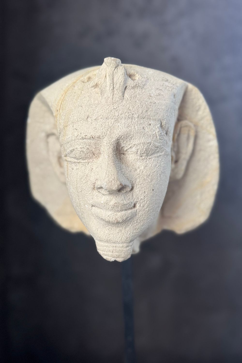 Close-up detail of the stone pharaoh head sculpture, emphasizing the carved facial details and smooth stone surface.