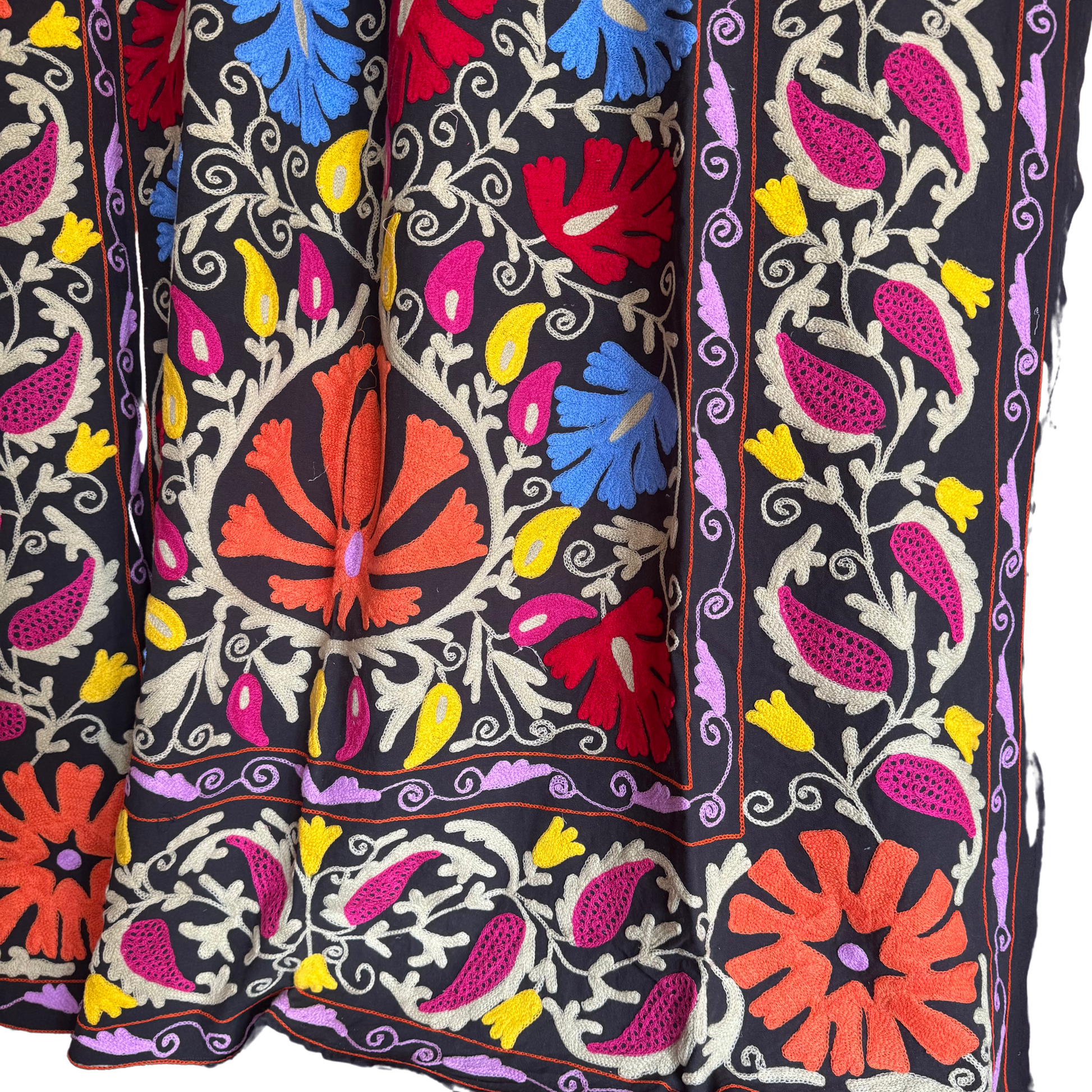 Close-up of lilac and purple embroidery in dense chain-stitch on washed-black ground