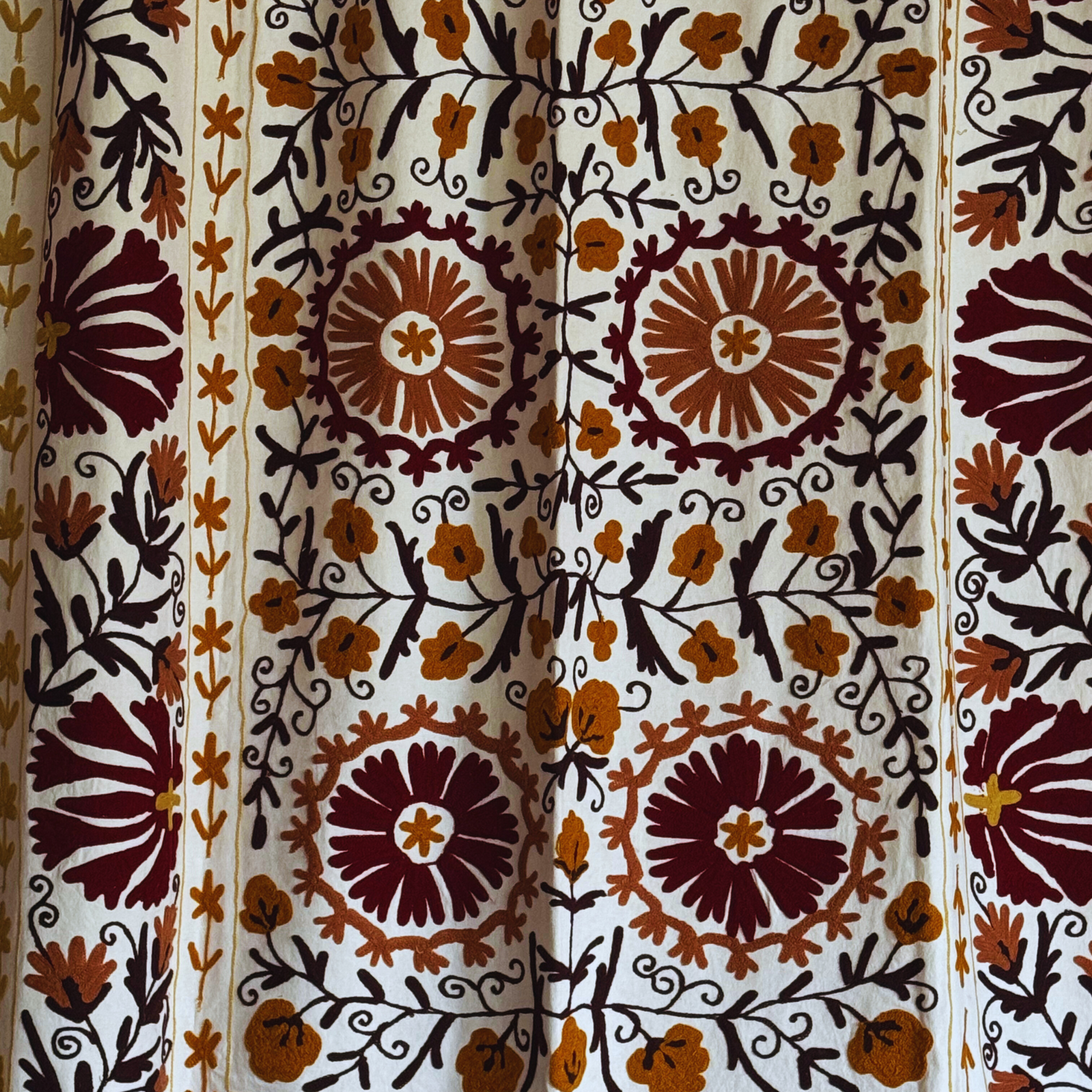 Close-up of Suzani floral embroidery with botanical vines in warm colours