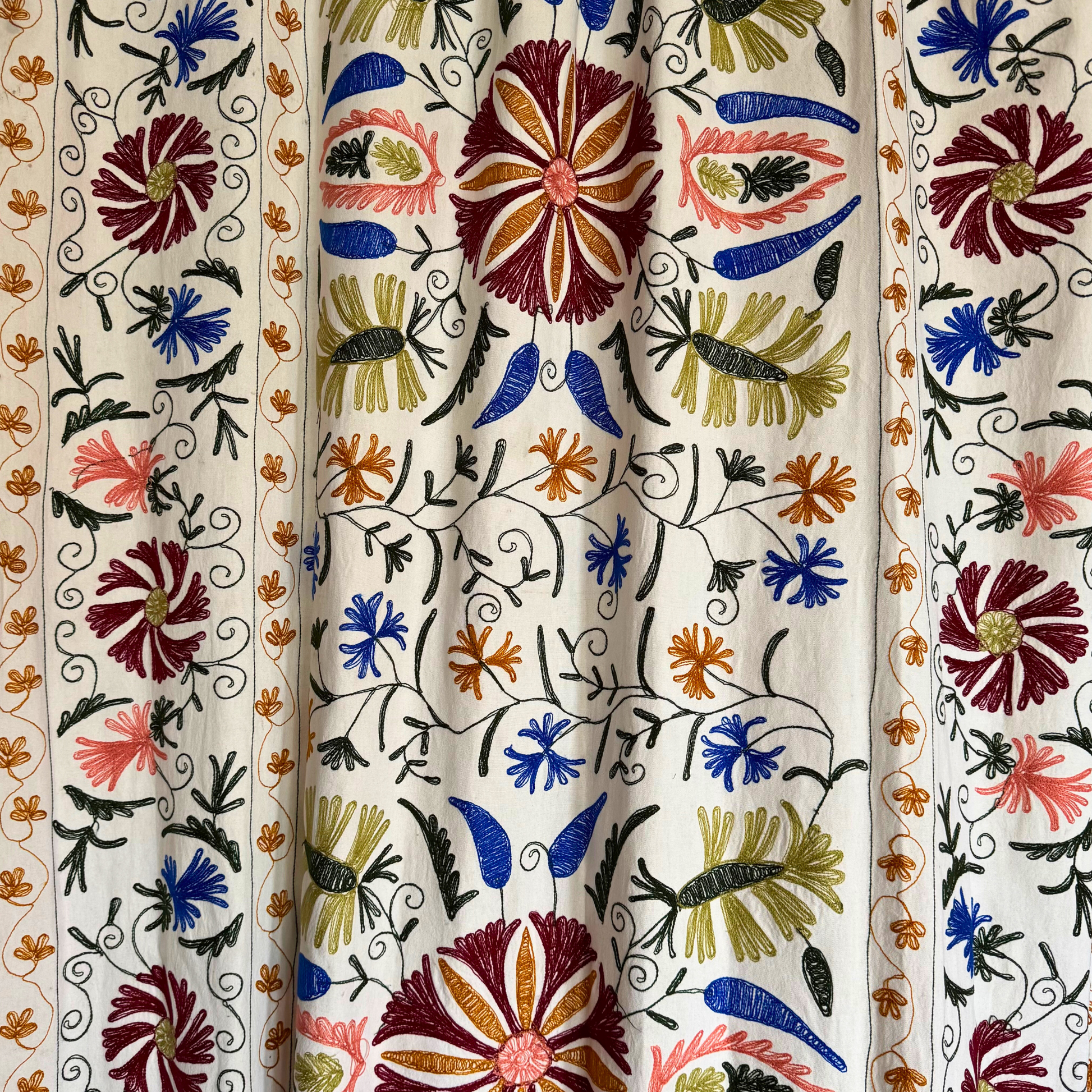 Suzani used as wall hanging behind console table in bright, modern interior